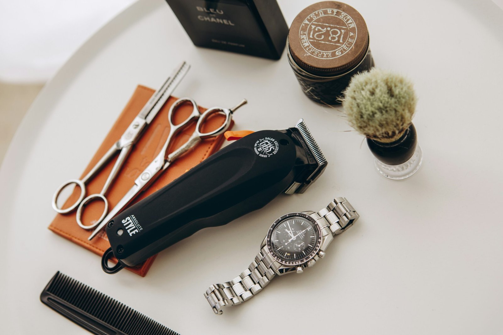 silver link bracelet round analog watch beside black leather pouch and silver and gold link bracelet